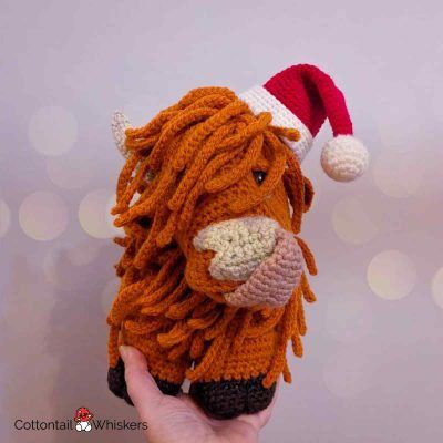 Highland cow with a free christmas crochet santa hat pattern by cottontail and whiskers